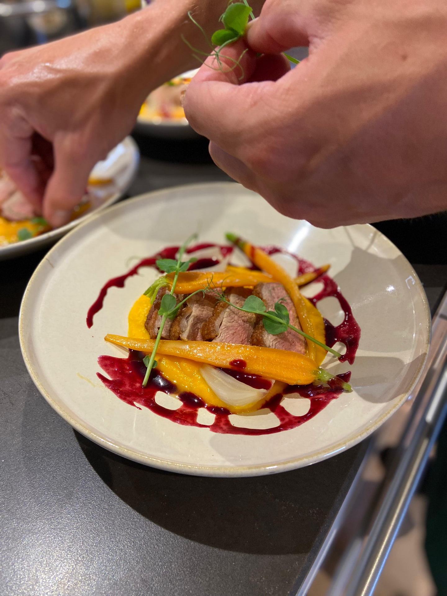 Private chef adding fresh herbs while plating a colourful main course