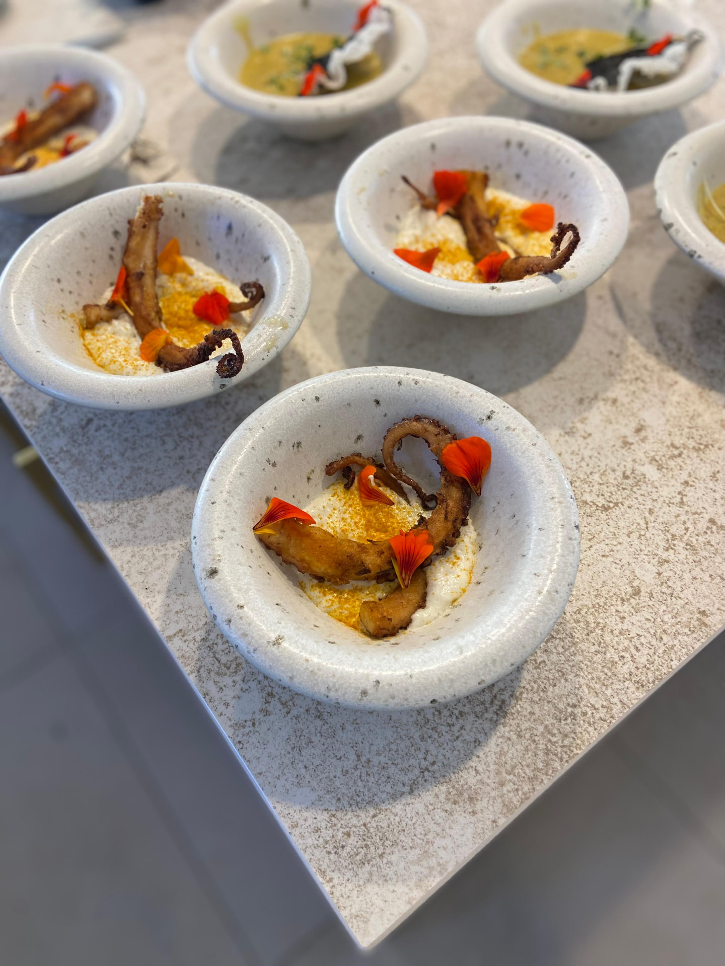 Individual octopus starters plated in ceramic bowls for a private dining event
